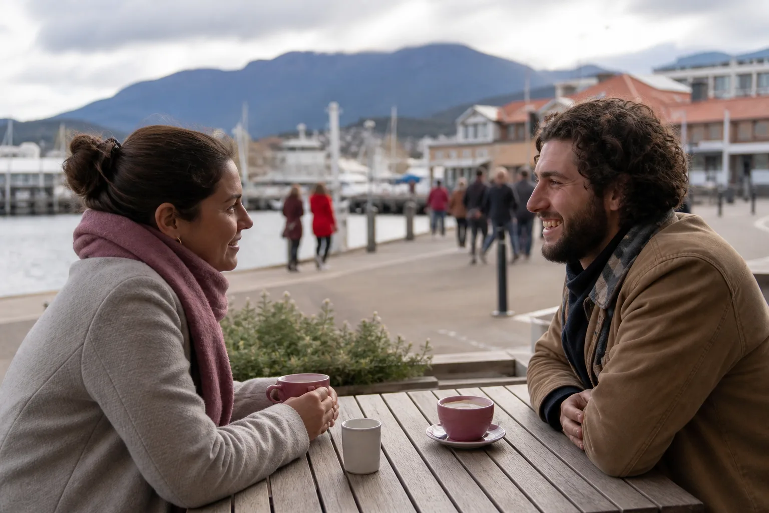 Two people talking over coffee at a waterfront cafe in Hobart