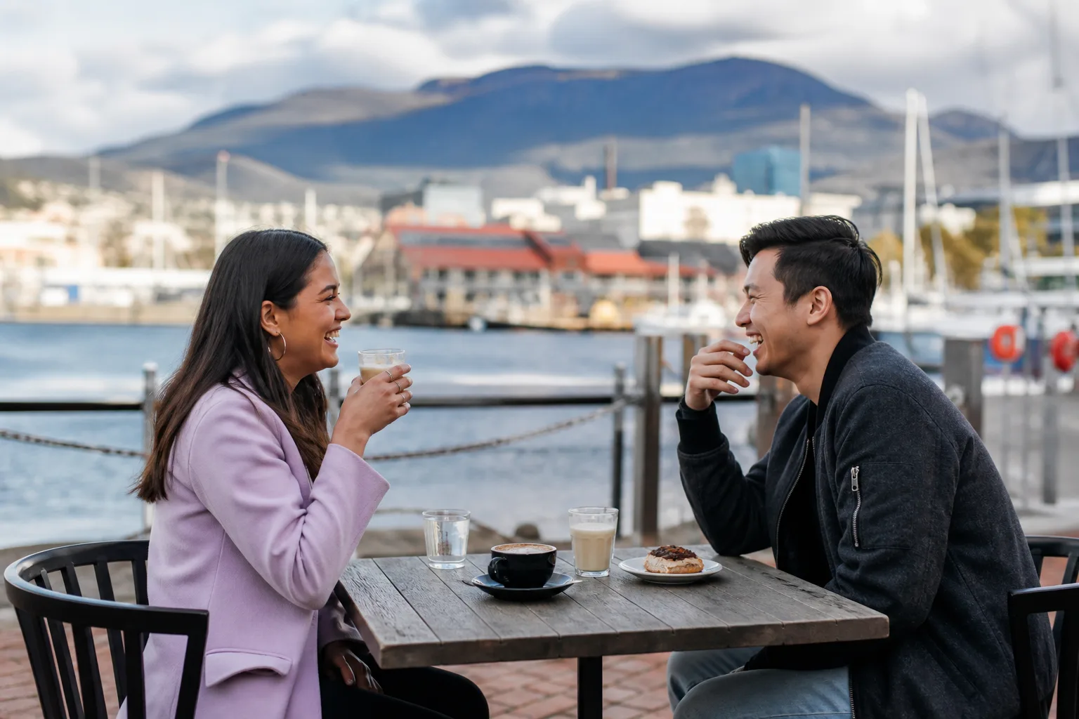 Couple walking beside Hobart waterfront with kunanyi in the distance